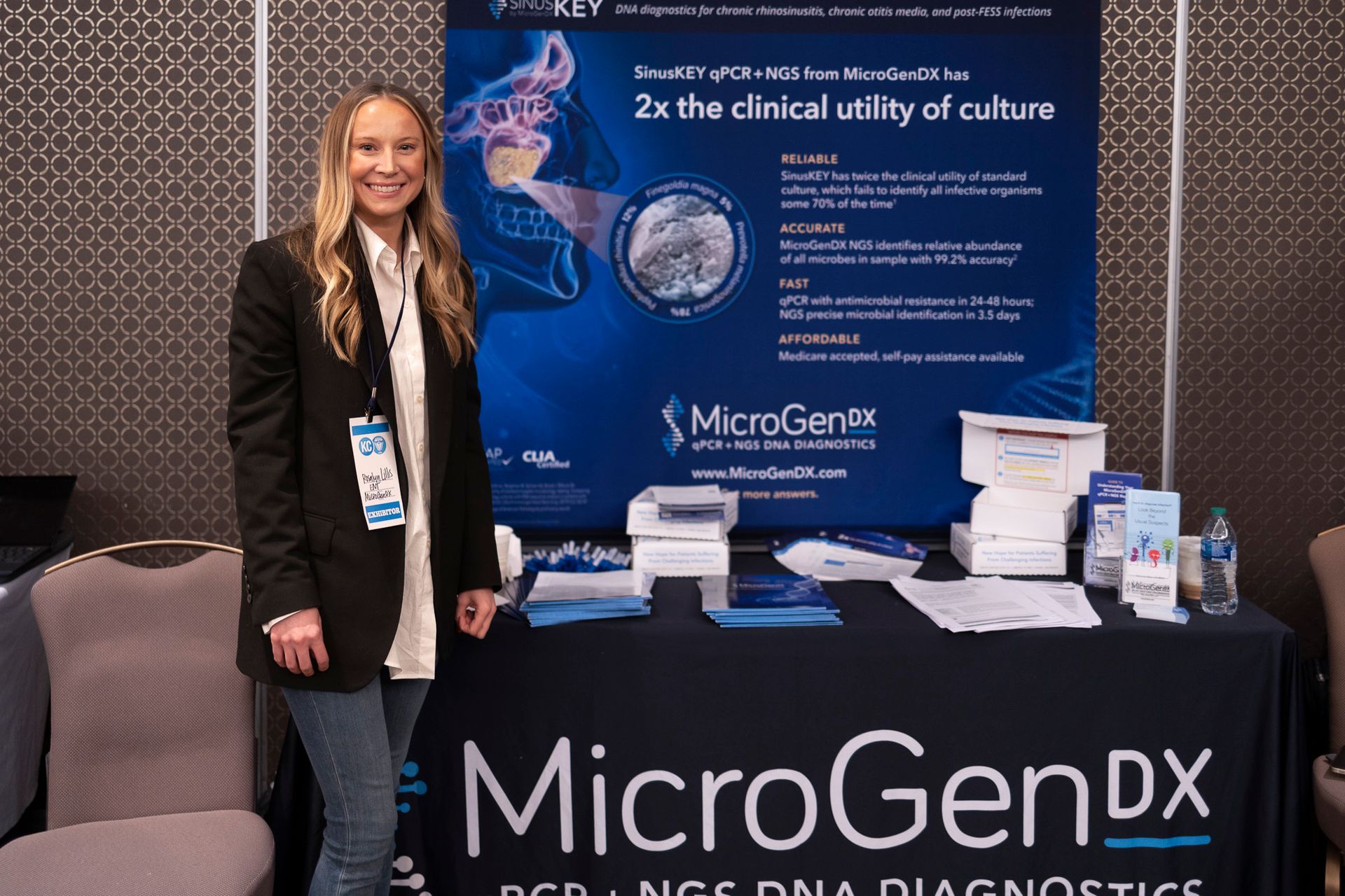 A woman is standing in front of a microgen dx table.